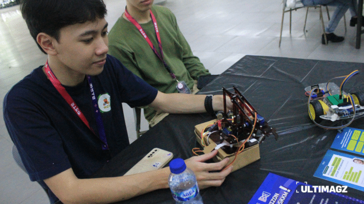 Dua orang mahasiswa selaku kreator dari robot interaktif yang dipamerkan pada pameran BYTE di Lobby D PK Ojong, Universitas Multimedia Nusantara pada Senin (3/11/25). (ULTIMAGZ/Tiffany Michiko P)