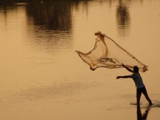 nelayan yang sedang menebarkan jala