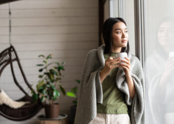 Ilustrasi seseorang sedang bersantai dekat jendela sebagai representasi gaya hidup slow living.