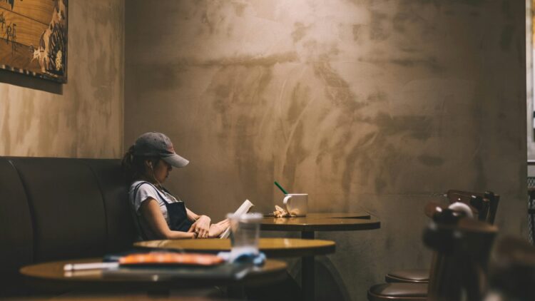 Ilustrasi perempuan yang sedang membaca buku di kafe. (Unsplash/@Bundo Kim)